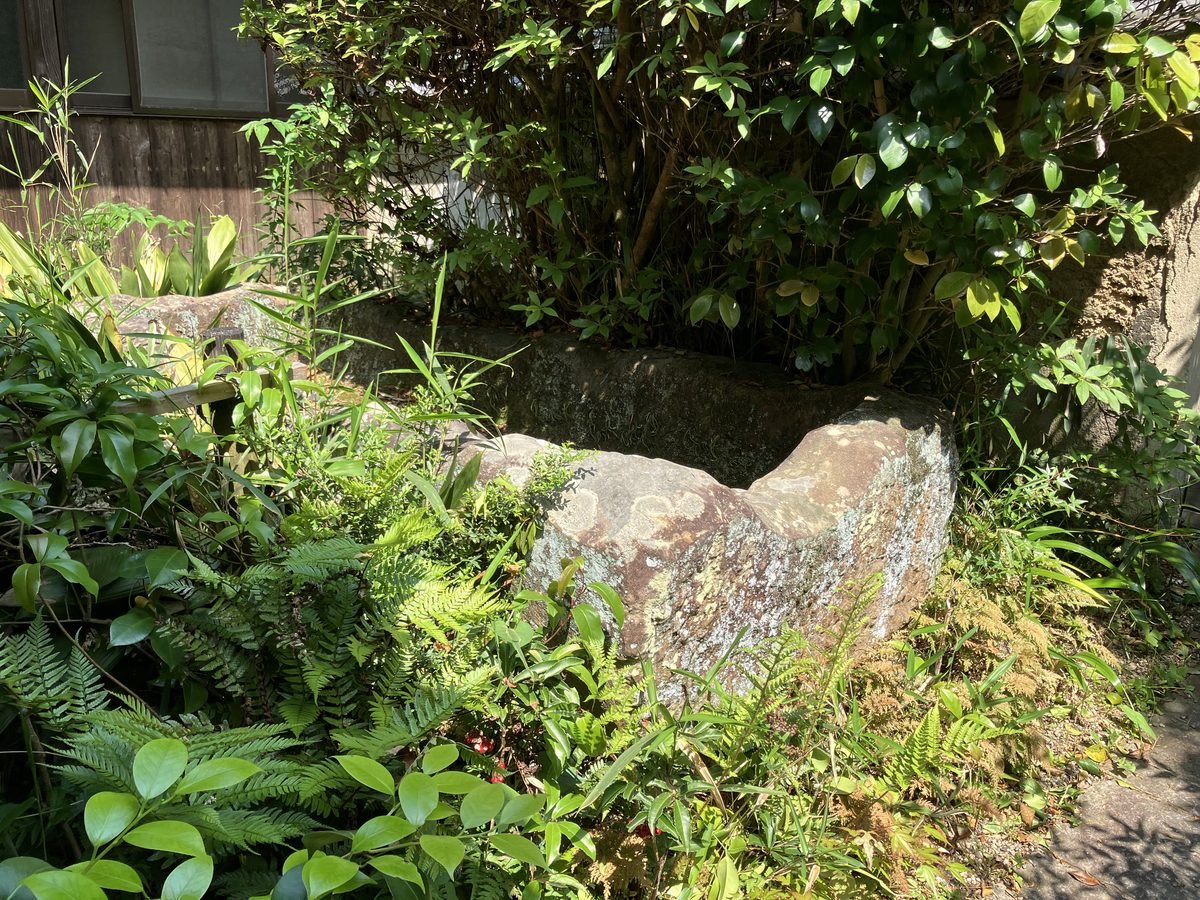 An ancient stone coffin from a burial mound, surrounded by greenery in the grounds of Futaiji