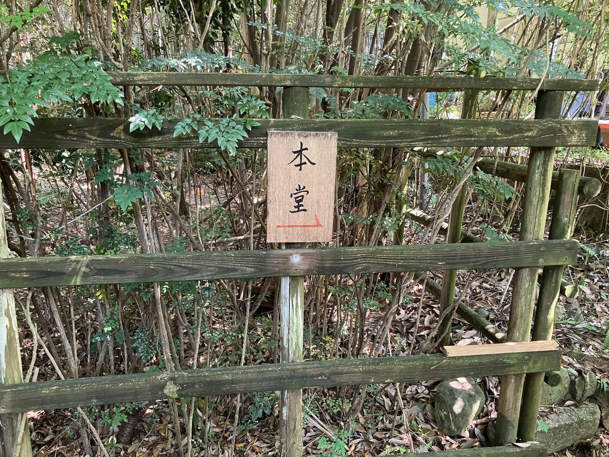 A wooden sign reading Main Hall in Japanese, with a red arrow pointing right